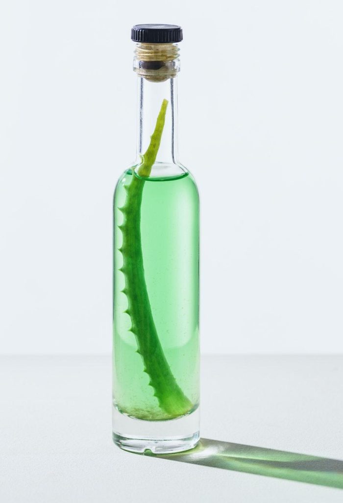 bottle of natural herbal essential oil with aloe vera on white cube